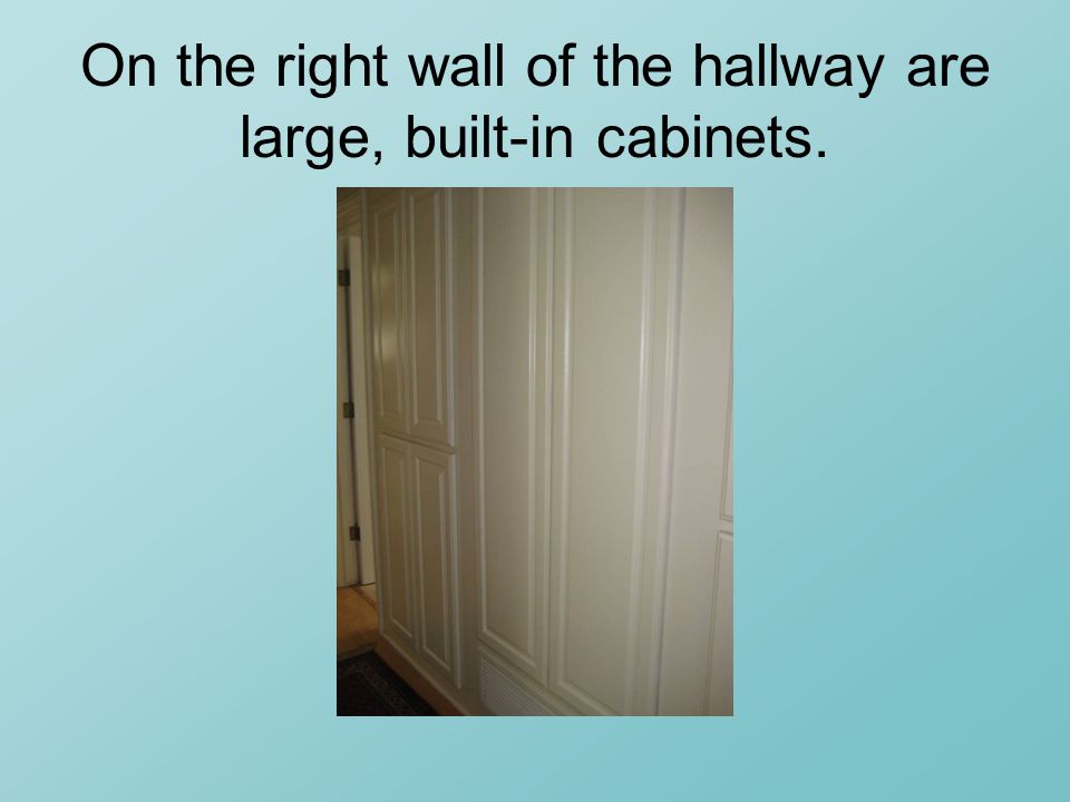 On the right wall of the hallway are large, built-in cabinets.