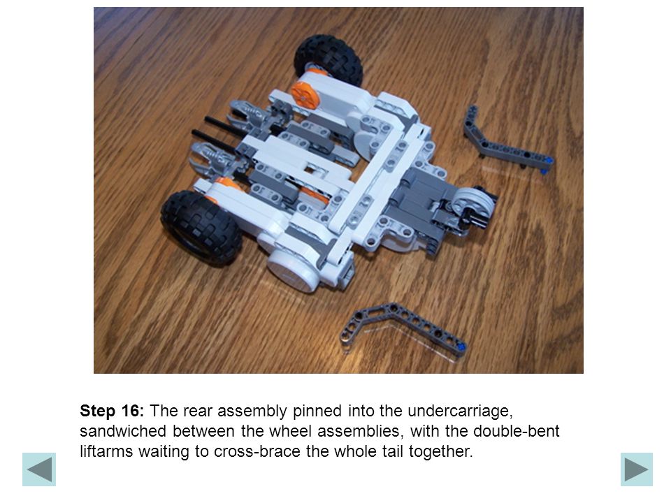 Step 16: The rear assembly pinned into the undercarriage, sandwiched between the wheel assemblies, with the double-bent liftarms waiting to cross-brace the whole tail together.