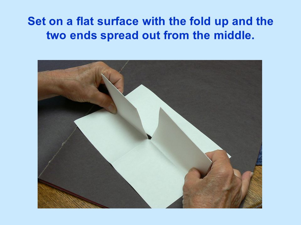 Set on a flat surface with the fold up and the two ends spread out from the middle.