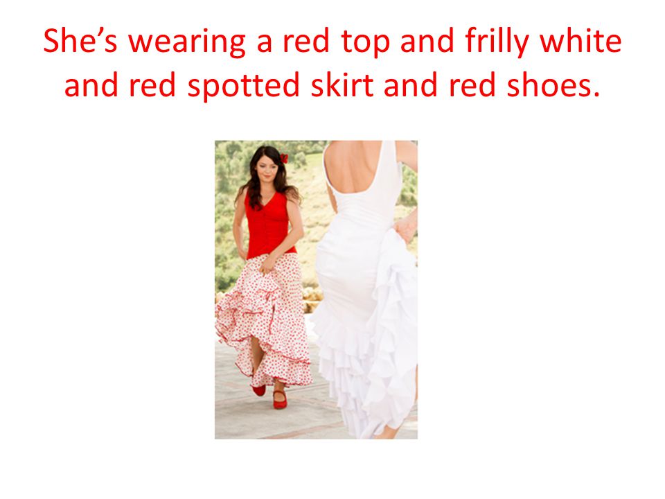 She’s wearing a red top and frilly white and red spotted skirt and red shoes.