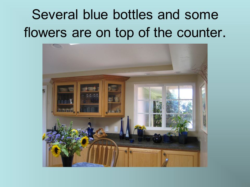 Several blue bottles and some flowers are on top of the counter.