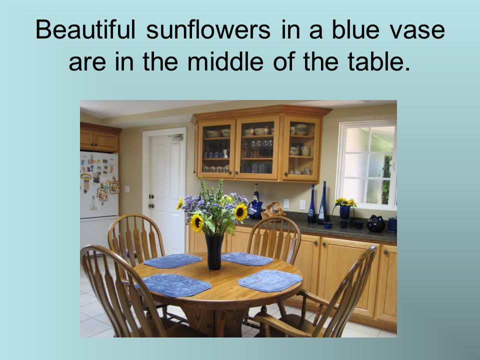 Beautiful sunflowers in a blue vase are in the middle of the table.