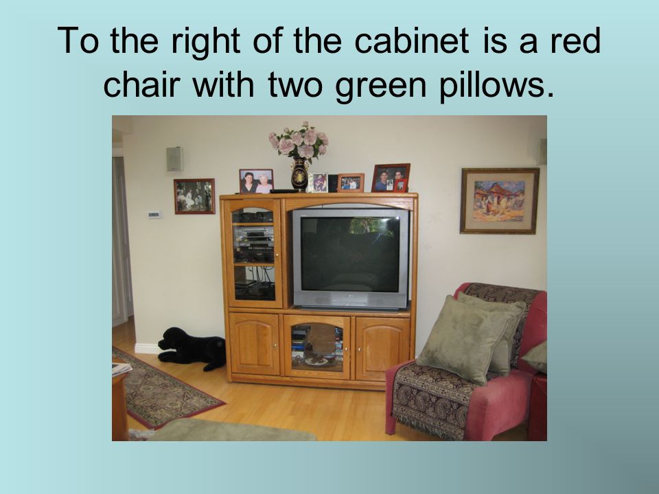 To the right of the cabinet is a red chair with two green pillows.