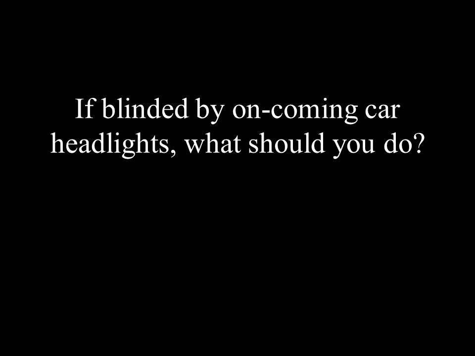 If blinded by on-coming car headlights, what should you do