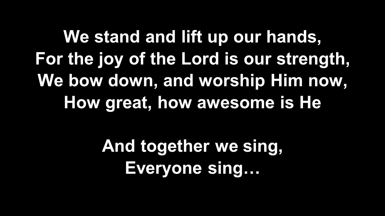 We stand and lift up our hands, For the joy of the Lord is our strength, We bow down, and worship Him now, How great, how awesome is He And together we sing, Everyone sing…