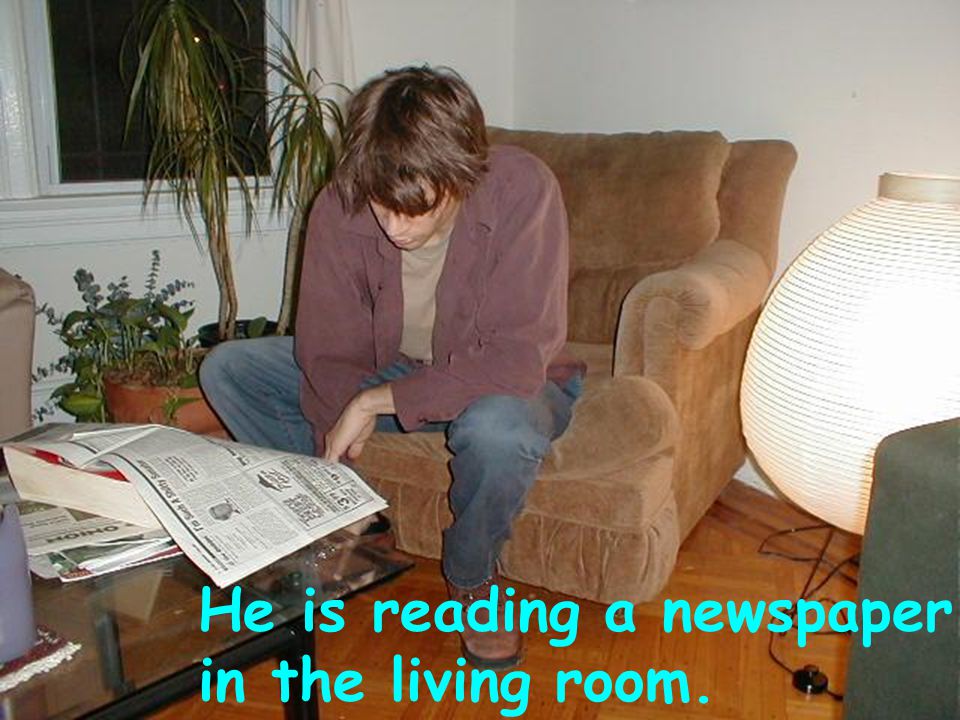 He is reading a newspaper in the living room.