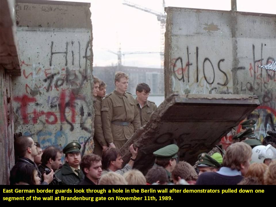 A circus bear on its hind legs crosses into West Berlin with its handler through a section of the Berlin wall that was taken down at Potsdamer Platz on November 11th, 1989.